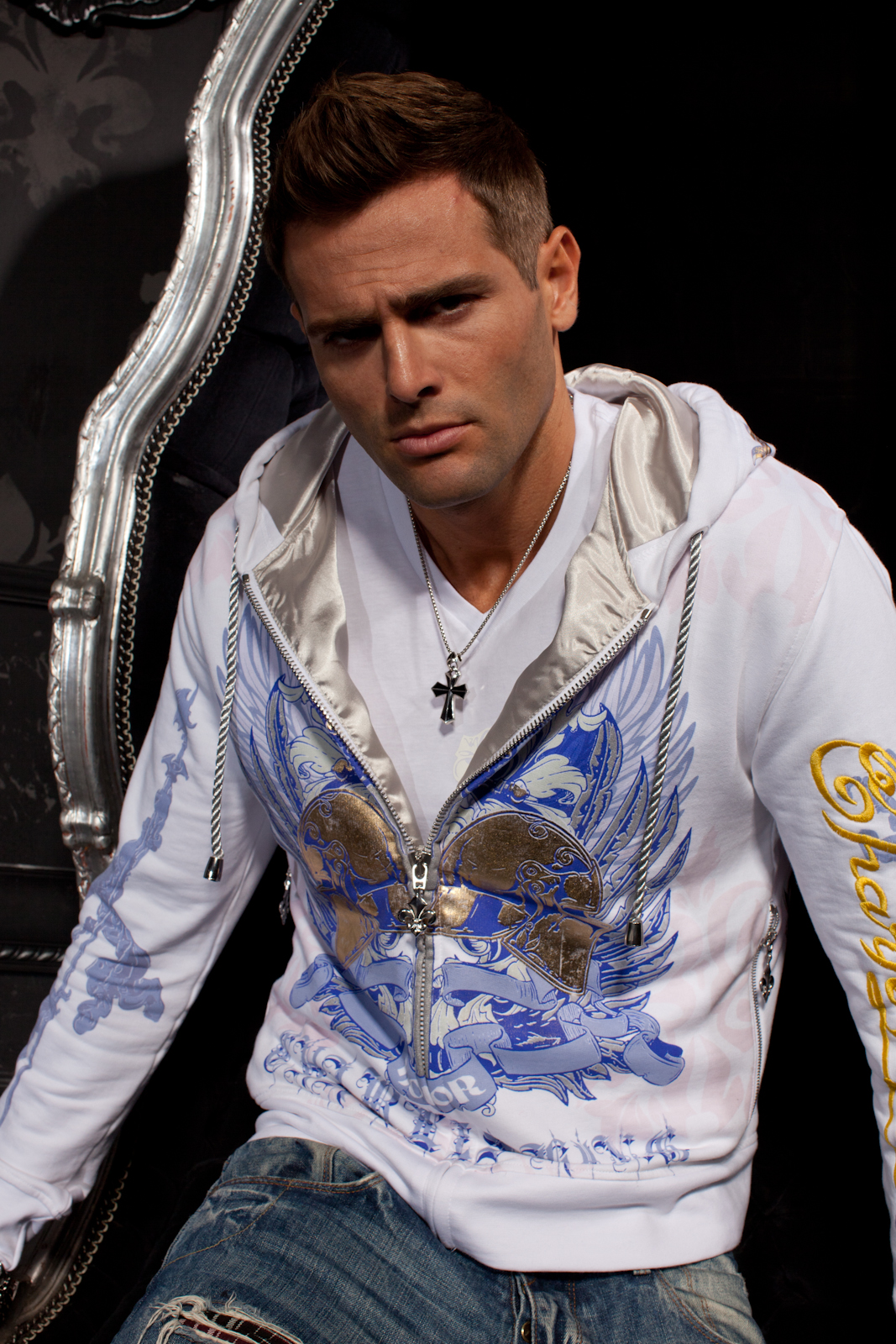 Man in a white Charles King Paris hoodie seated in a silver baroque chair